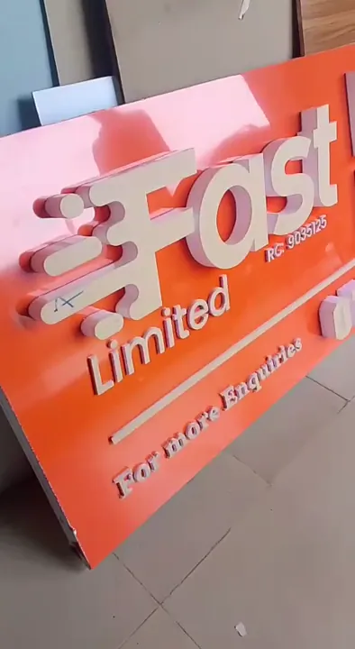 Fabricated 3D acrylic letters mounted on an orange commercial fascia tray in the Lagos workshop.