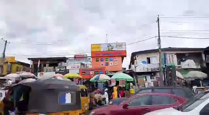 realme branded commercial billboard and orange shopfront fascia in a busy Lagos market district.