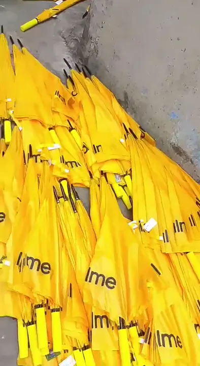 Large batch run of yellow realme branded folding umbrellas stacked on the workshop floor in Lagos.